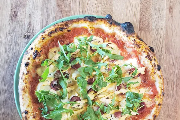 July Pizza Premium Snake River Farms Kobe hot dogs, crispy potato, fresh mozzarella, provolone, parmesan, peppery arugula, and a sweet-hot kick of Mama Lil's chilis, all on our OG tomato sauce.